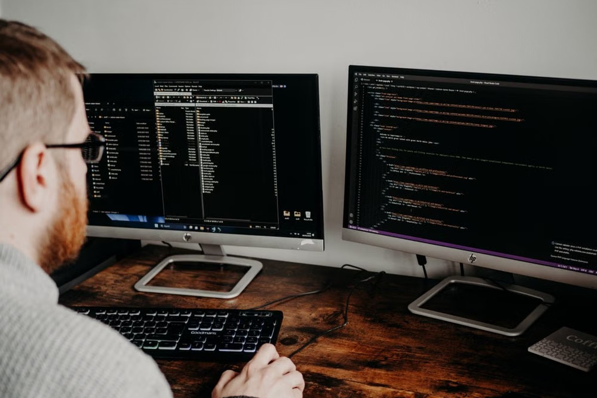 Developer working across dual monitors with code and file systems